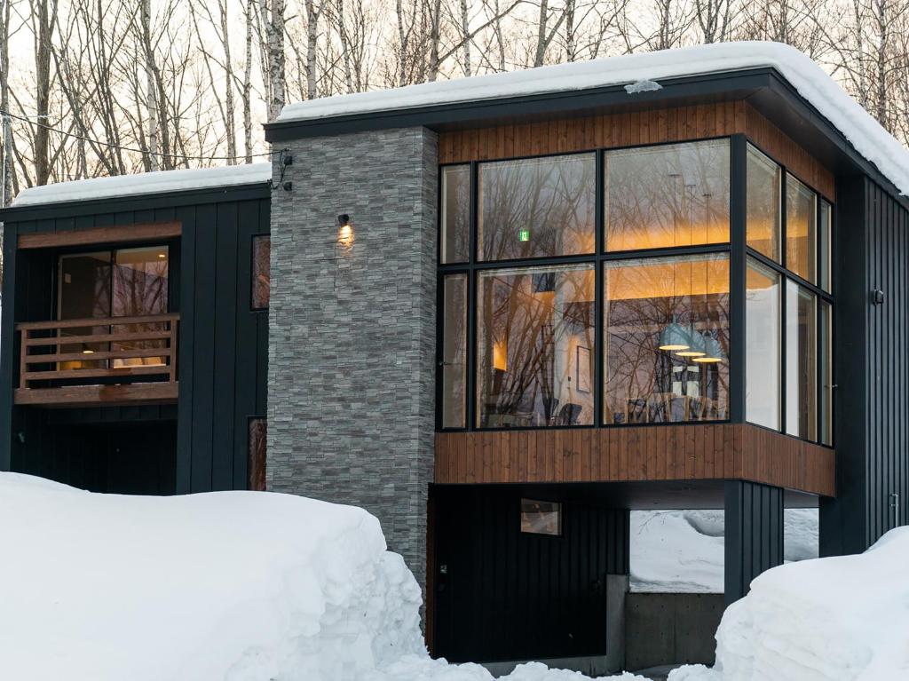 a small house with glass windows in the snow at Chalet Ukiyo in Niseko