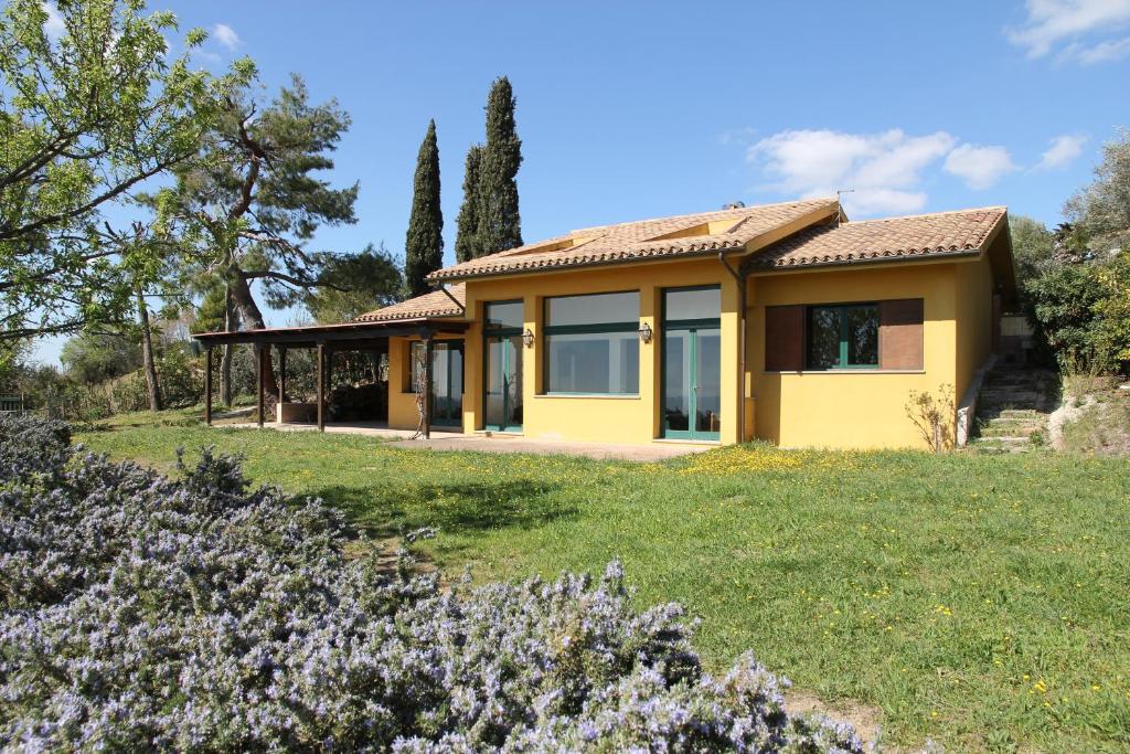 ein gelbes Haus auf einem grünen Feld mit Blumen in der Unterkunft Villa Panorama Sirolo in Sirolo