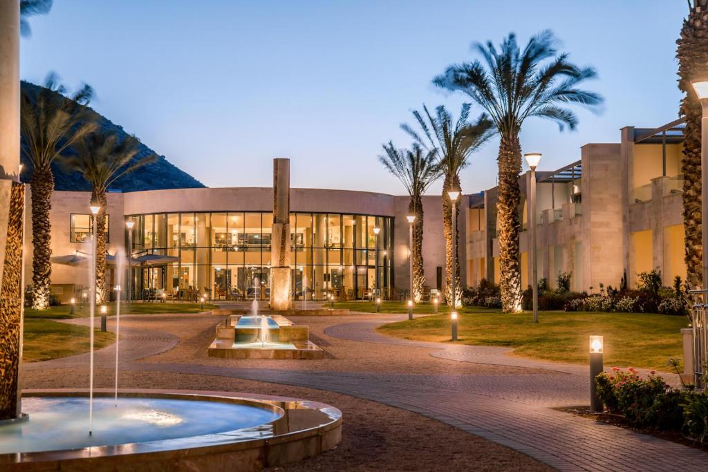 a building with a fountain and palm trees in front at Magdala Hotel in Migdal