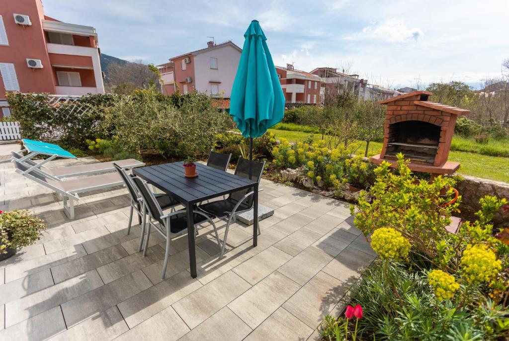 a patio with a table and a blue umbrella at Apartment Magic Garden in Baška