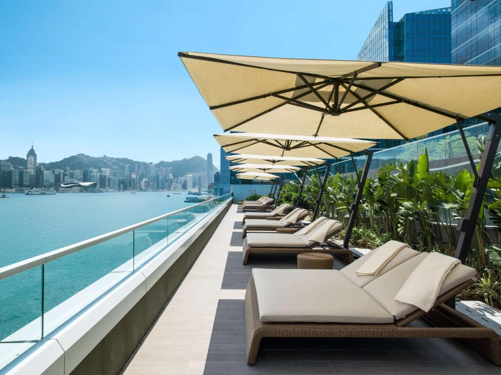 a row of lounge chairs and umbrellas on a balcony at Kerry Hotel, Hong Kong in Hong Kong
