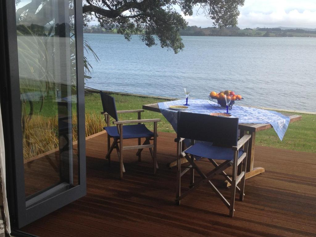 une table sur une terrasse avec vue sur l'eau dans l'établissement Absolute Waterfront Serenity Near Auckland, à Clarks Beach