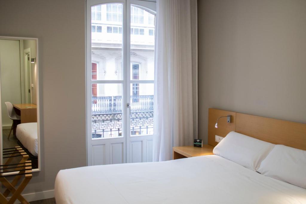 - une chambre avec un lit blanc et une fenêtre dans l'établissement Alda Alborán Rooms, à La Corogne