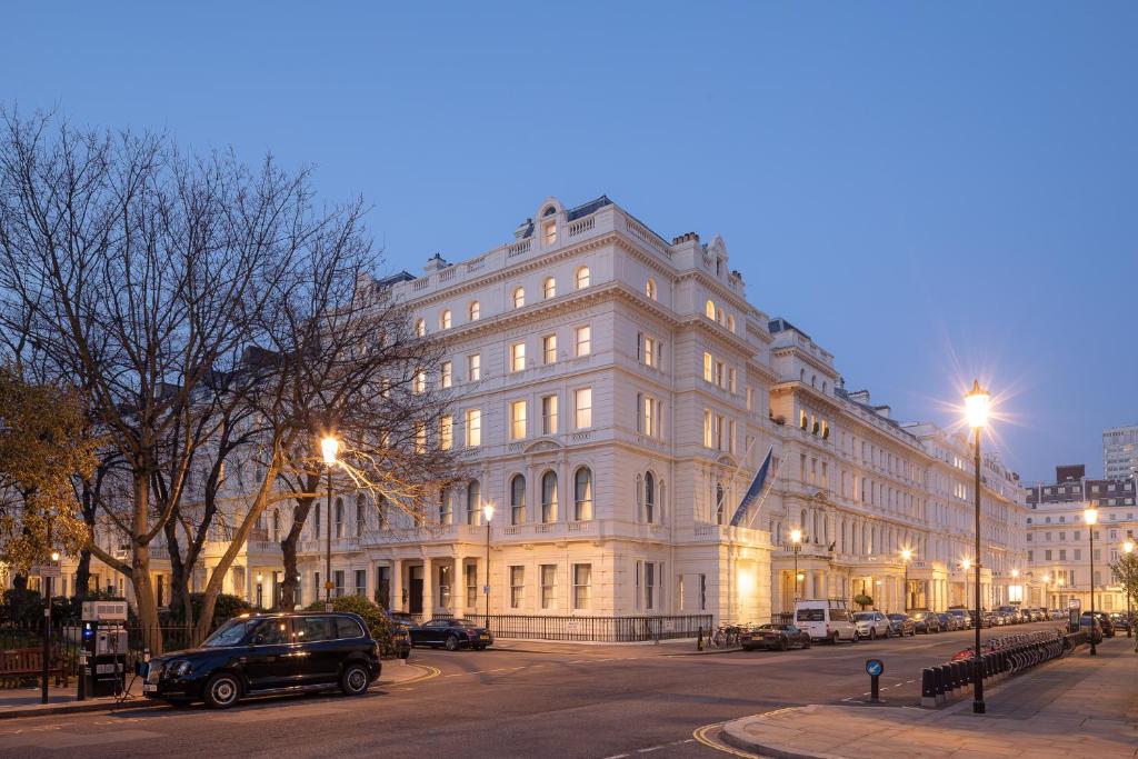 duży biały budynek na ulicy miejskiej w nocy w obiekcie Hapimag Apartments London w Londynie