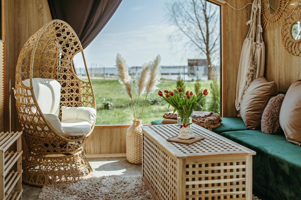 salon z kanapą, krzesłami i oknem w obiekcie Herbals - Tree&Lake houses with bath, sauna, bikes w mieście Mielno