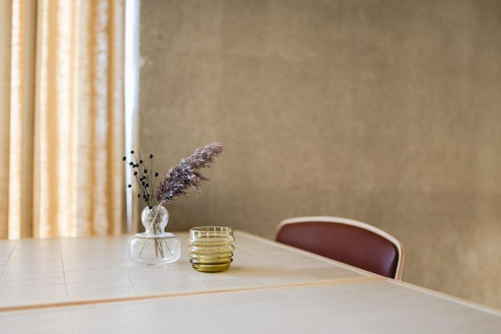 a table with a vase of flowers and a candle on it at VALO Hotel & Work Helsinki in Helsinki