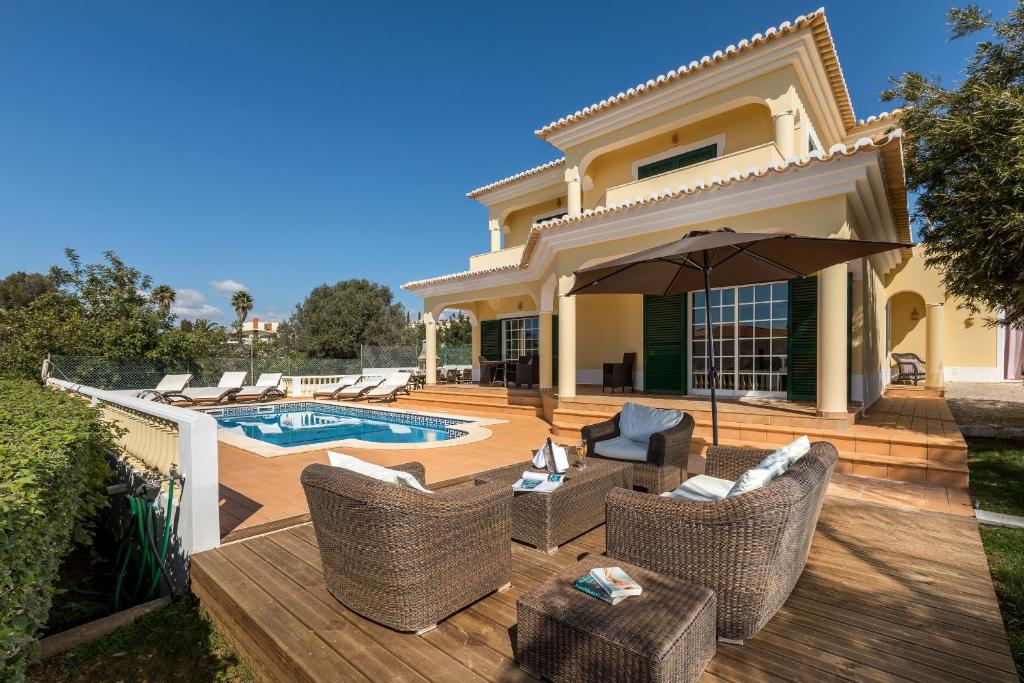 um pátio com cadeiras e um guarda-sol ao lado de uma piscina em Casa da Praia em Ferragudo