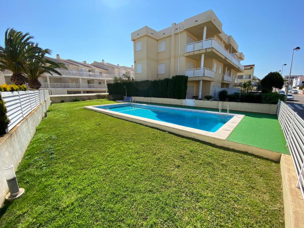 a yard with a swimming pool in front of a building at Apartamentos Playa Del Moro III Altamar in Alcossebre