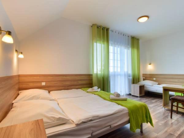 a bedroom with a large bed with green curtains at Nartorama HotRest in Zieleniec