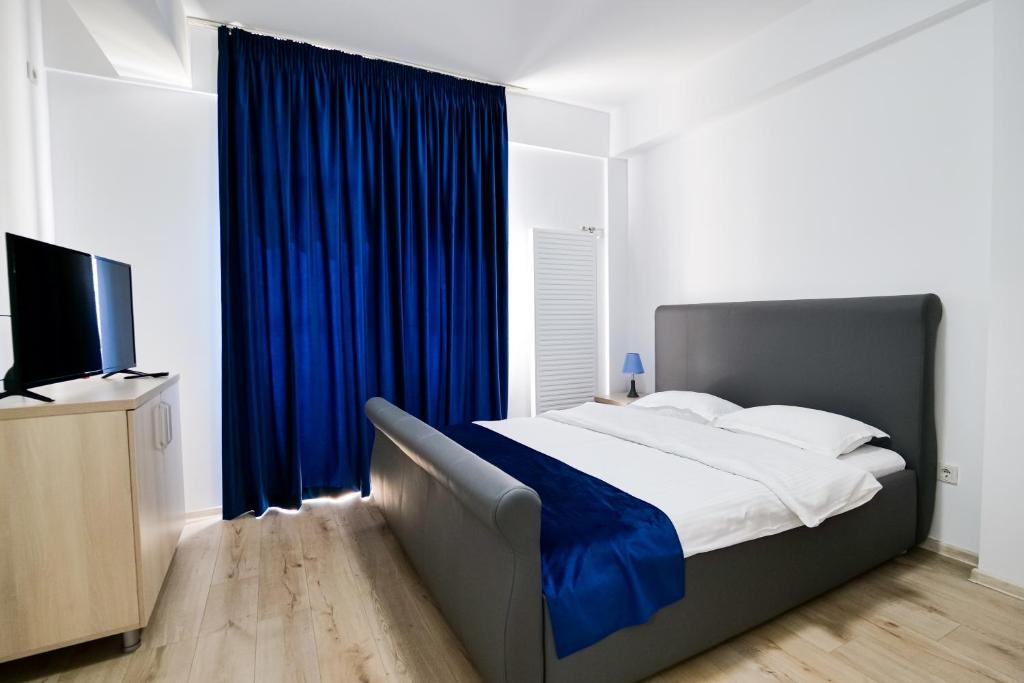 a bedroom with a bed with blue curtains and a television at Hotel Ema&Zain in Bucharest