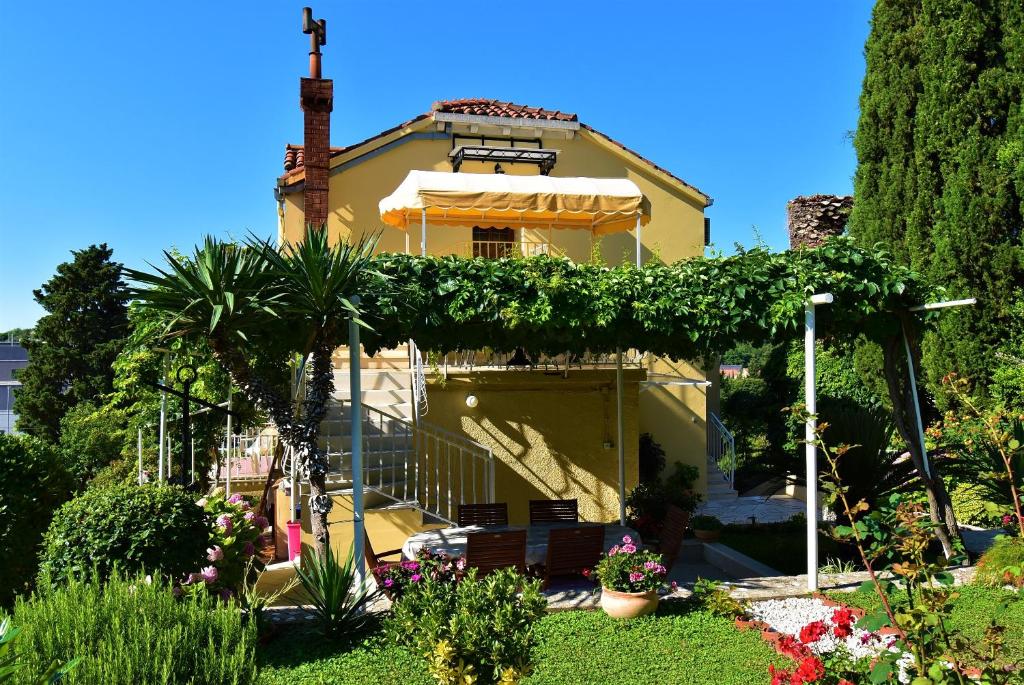une maison jaune avec un parapluie et quelques plantes dans l'établissement Guesthouse Kanjuo, à Mlini
