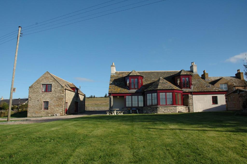 a large house with red windows on a green yard at Craiglea Lodge & Barn in Latheron