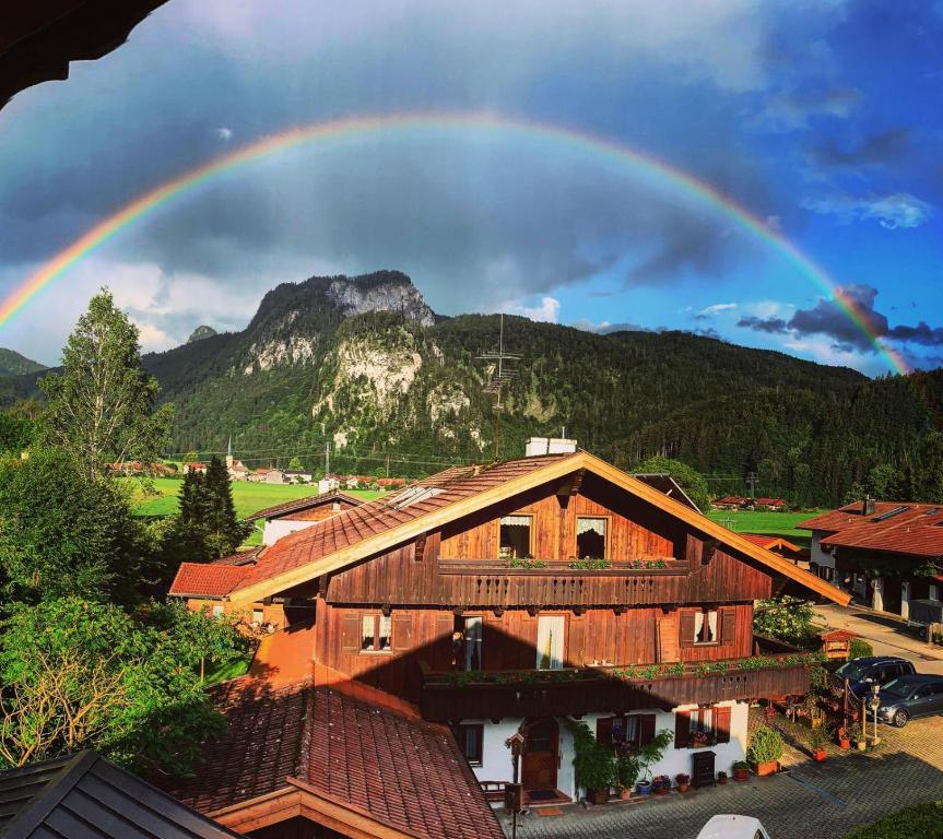 a rainbow over a wooden house with a mountain at Gästehaus Taubensee in Oberwössen