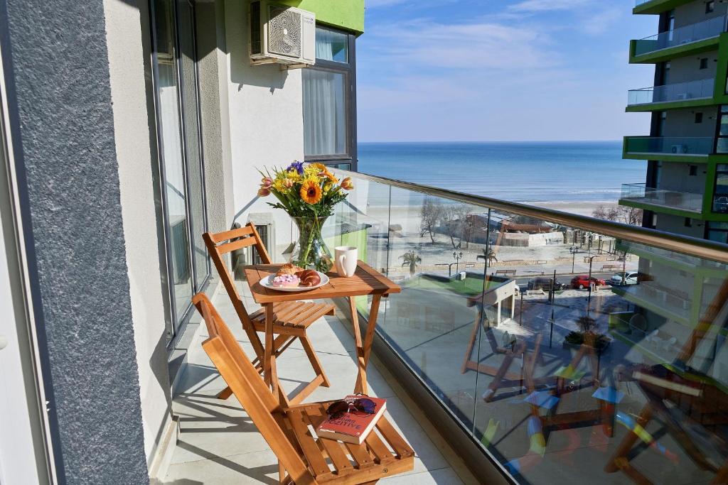 a balcony with a table and a vase of flowers at Glamour Sea view Family Apartments - Spa n Pools Resort in Mamaia