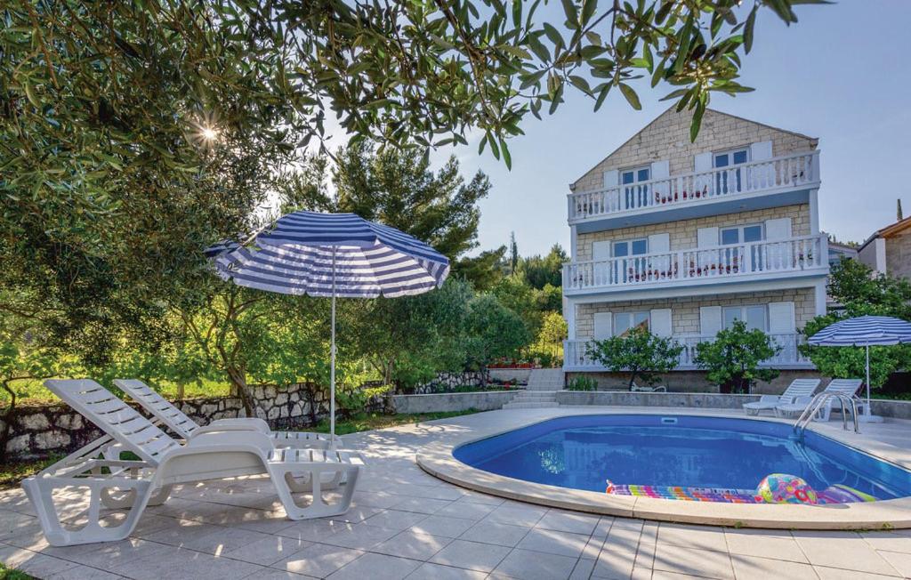 a pool with chairs and an umbrella and a building at Bijela Villa in Slano