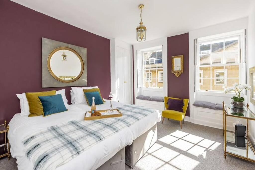 a bedroom with a large bed and a yellow chair at Georgian apartment located in the center of Bath. in Bath