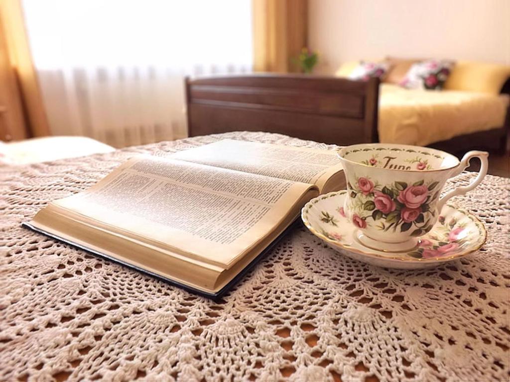 an open book on a table with a cup of coffee and a tea cup at Villa Iris in Kołobrzeg