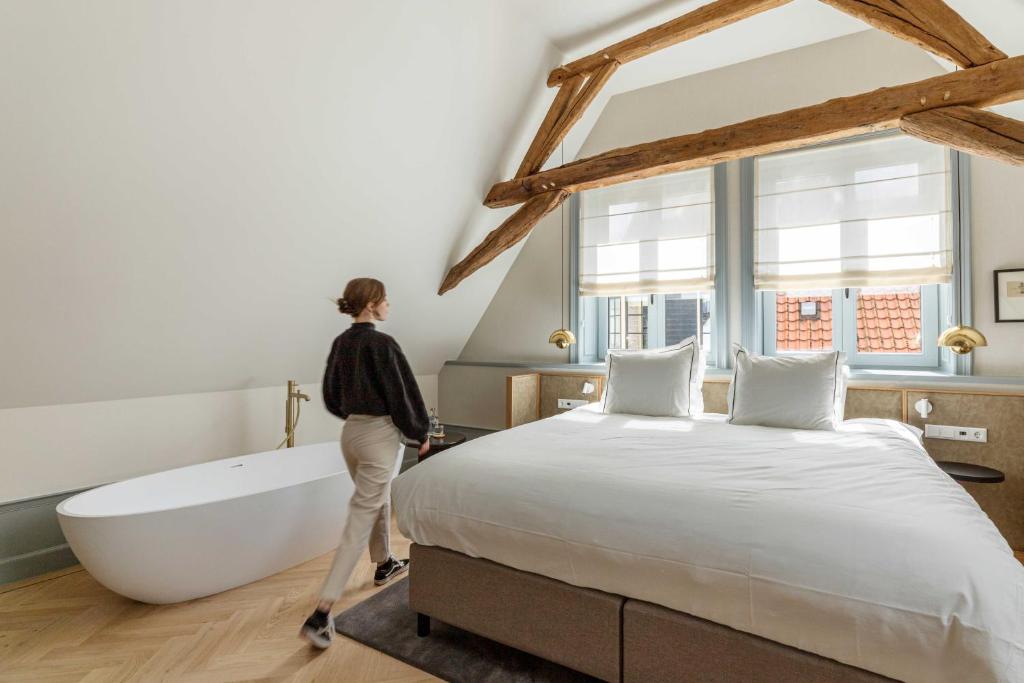 a woman walking through a bedroom with a bed and bathtub at Aparthotel Hattem in Hattem