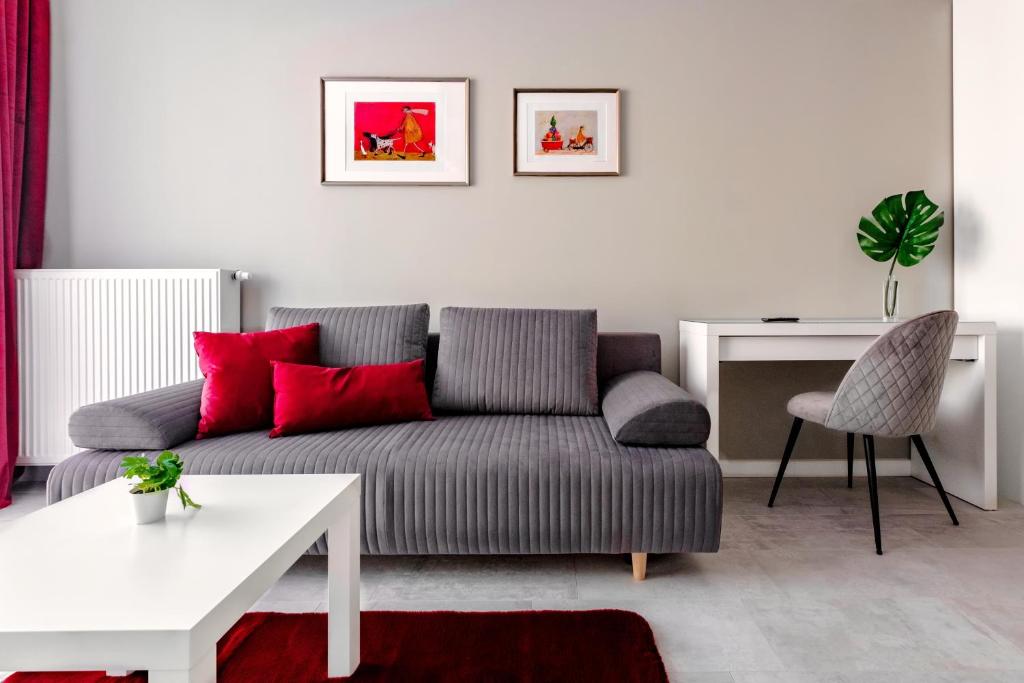 sala de estar con sofá gris y almohadas rojas en Apartamenty Saskie, en Lublin