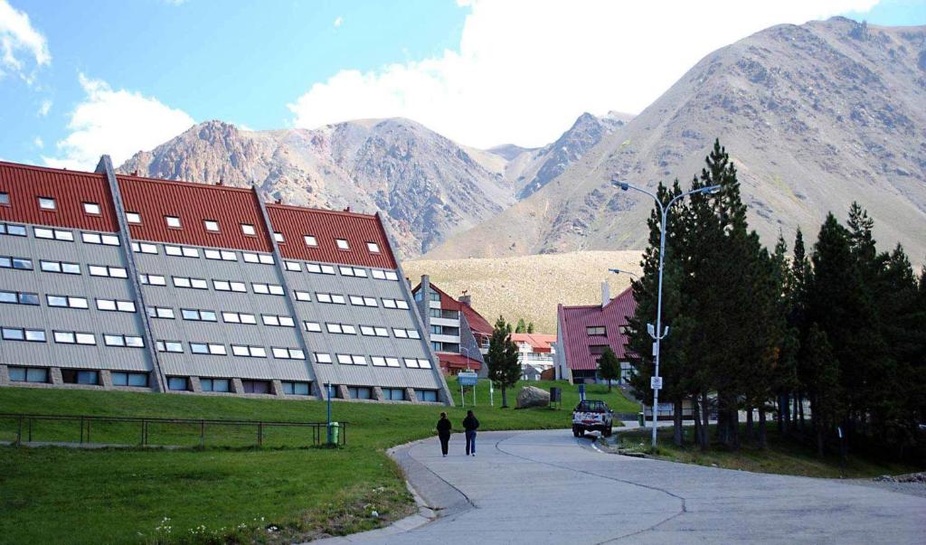 a building on a street with mountains in the background at Departamentos Las Leñas in Las Lenas
