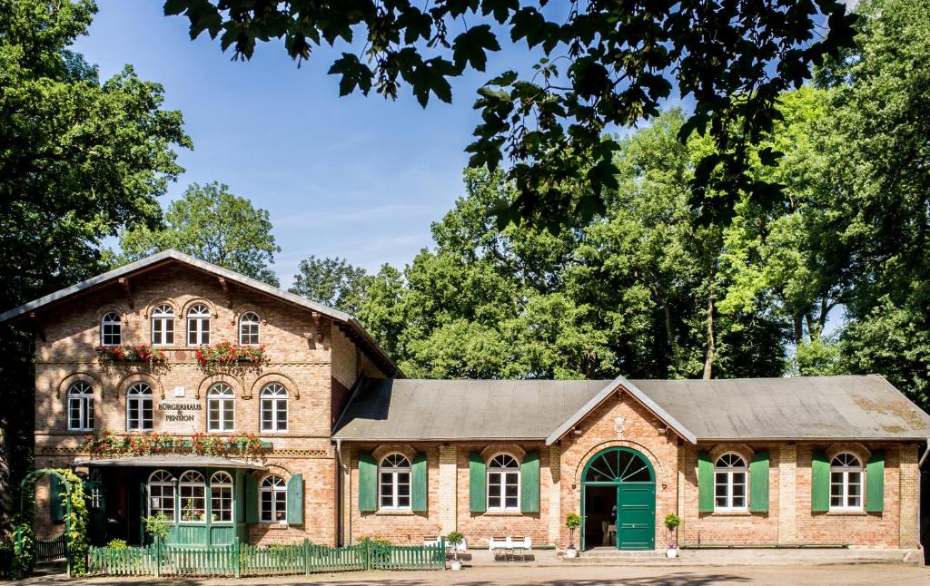 a brick building with a green door and trees at Bürgerhaus auf dem Hasenberg in Gützkow