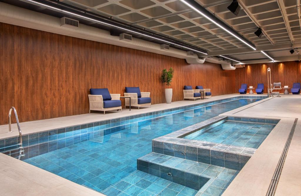 a pool in a hotel room with blue chairs at Meliá Paulista in Sao Paulo