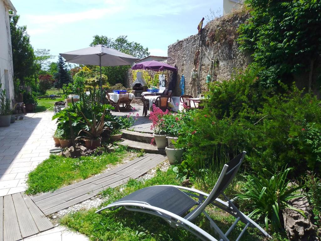 - un jardin avec une table, des chaises et un parasol dans l&#39;établissement GUEST HOUSE groupe et Famille, à Saint-Paimboeuf