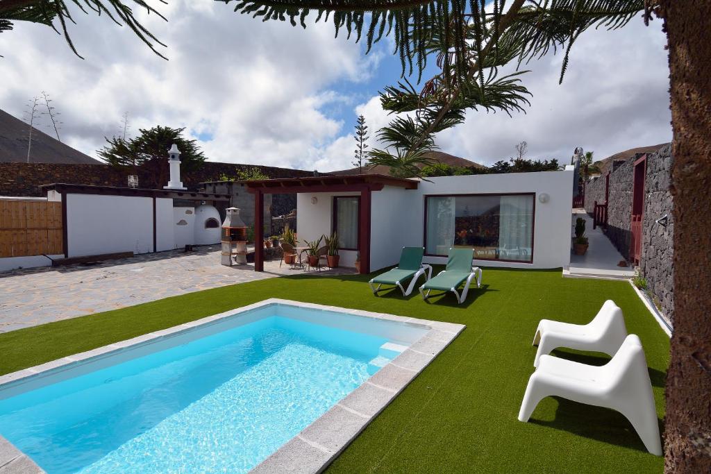 un patio trasero con piscina y césped verde en Villa Nelida peace lovers Vegueta By PVL, en La Vegueta