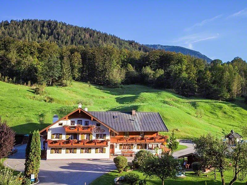 ein großes Haus mitten auf einem grünen Feld in der Unterkunft Ferienwohnungen Kilianmühle in Berchtesgaden