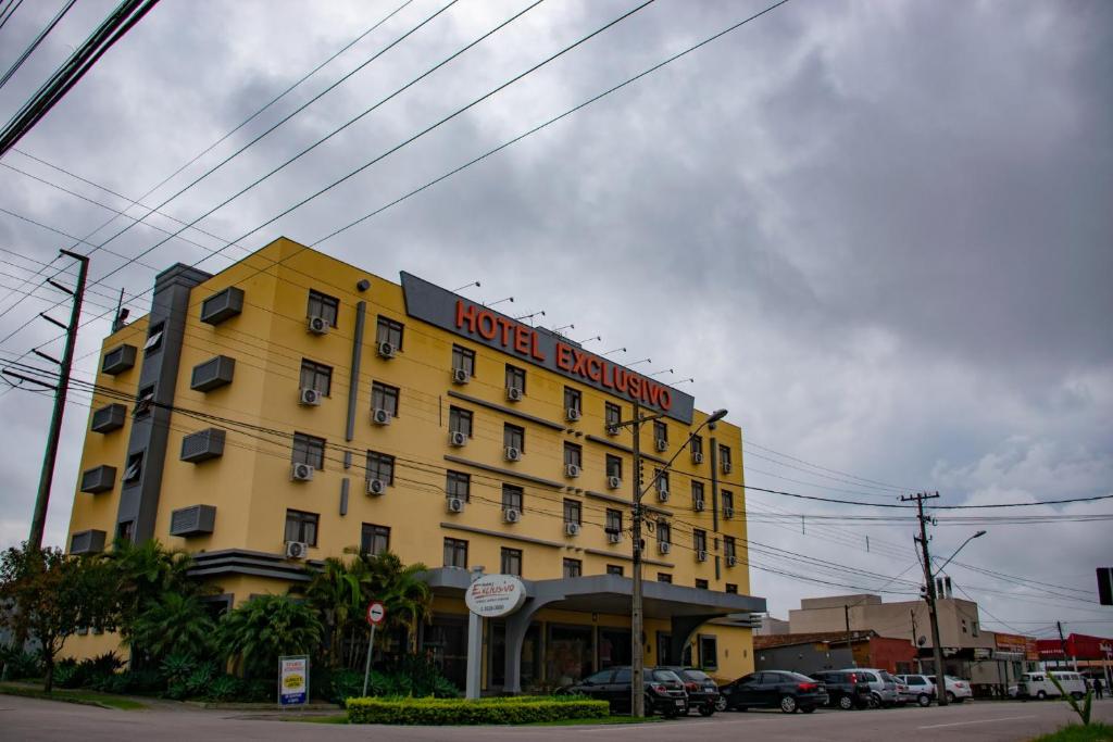 un edificio de hotel amarillo con un cartel de banquete del hotel en Hotel Exclusivo, en São José dos Pinhais