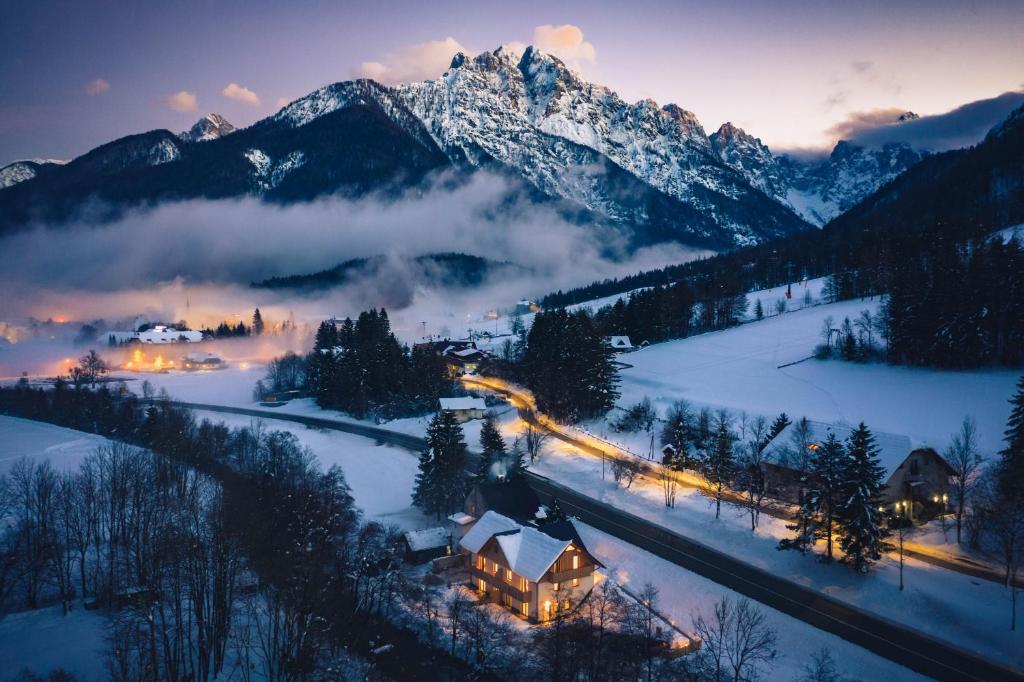 una casa en la nieve con montañas en el fondo en HIŠA KOSOBRIN, en Kranjska Gora