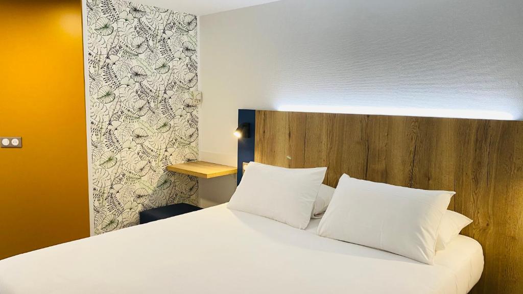 1 dormitorio con cama blanca y cabecero de madera en Kyriad Direct Chalon Sur Saone Nord, en Champforgeuil