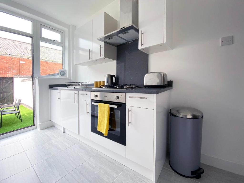 a kitchen with white cabinets and a stove top oven at The Baltic Townhouses by Serviced Living Liverpool in Liverpool