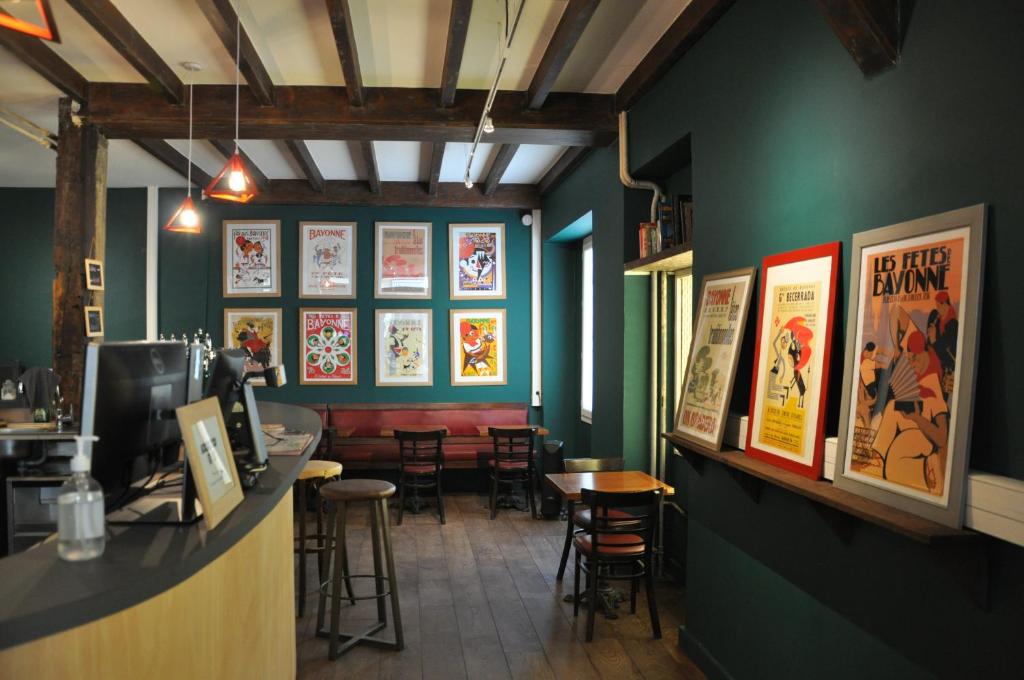 un restaurante con bar con taburetes y carteles en la pared en Hostel 20 Bayonne en Bayonne