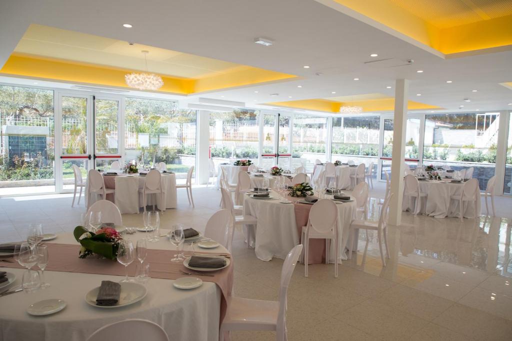 a banquet hall with white tables and chairs and windows at Principe Alogna Hotel & SPA in Altavilla Milicia