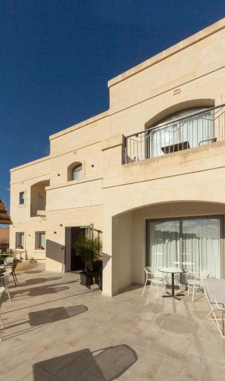a building with a patio with chairs and a table at Villa dei Venti in Qala