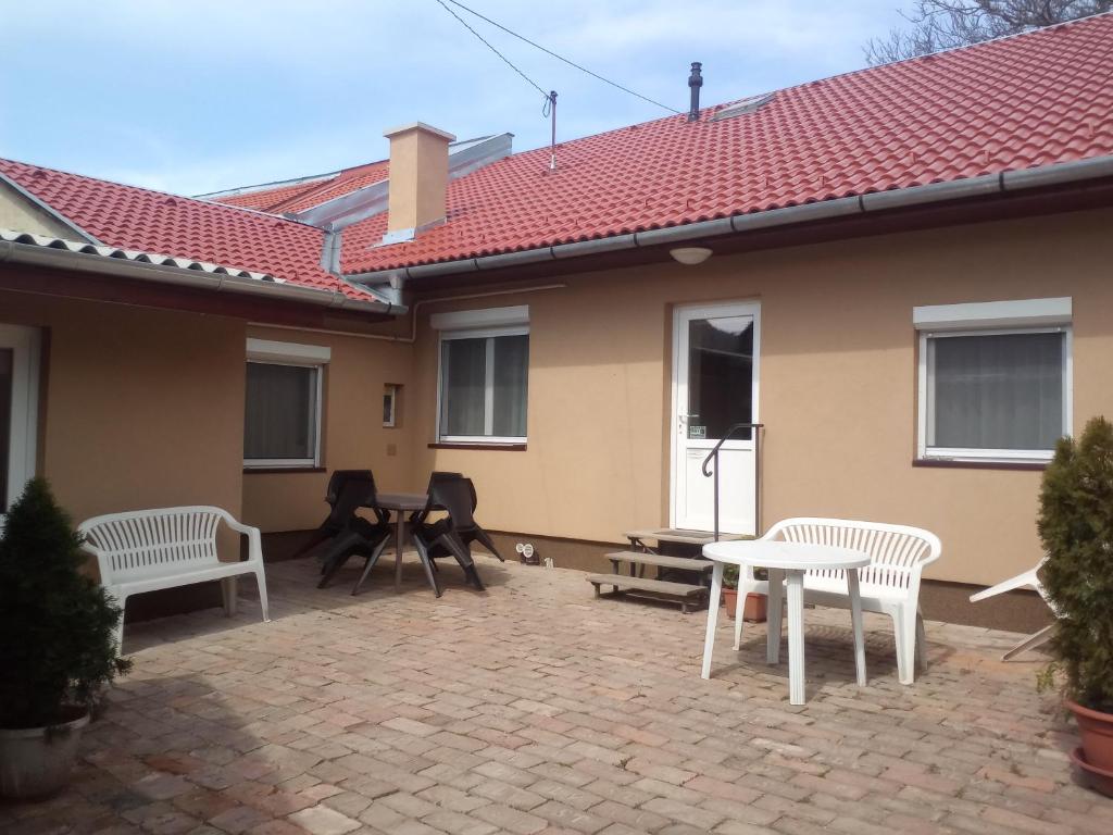 a patio with white chairs and a table and a house at START Apartmanok in Pécs