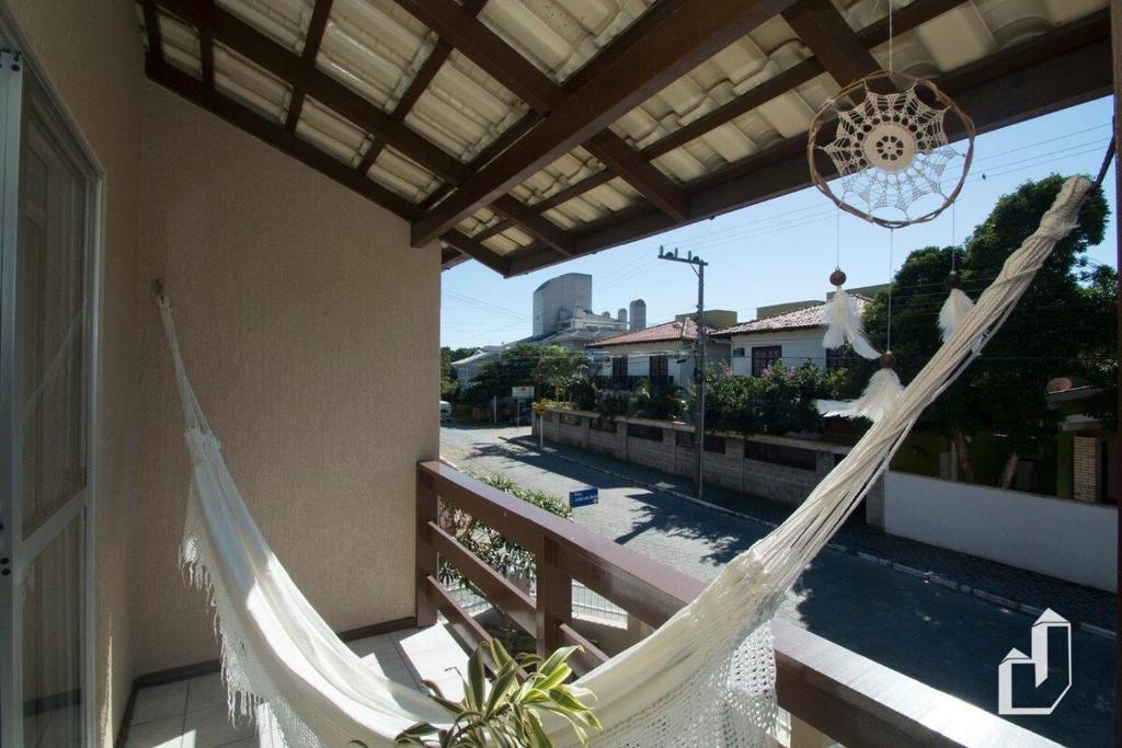 a hammock on a balcony with a view of a street at Casa com 03 dormitórios de casal in Bombinhas