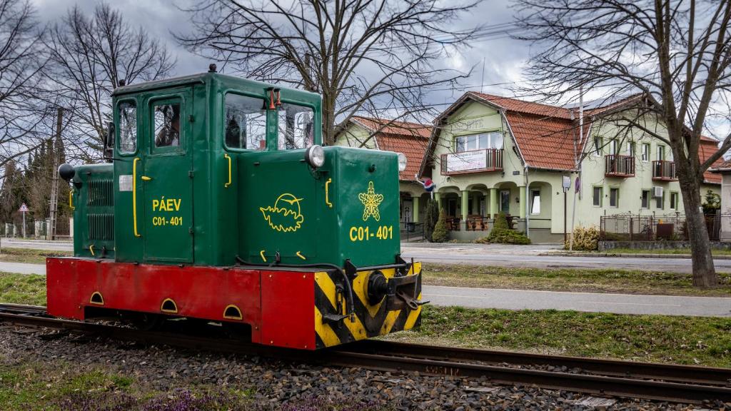 a green train car on the tracks in front of a house at Megálló Wellness Panzió in Pálháza