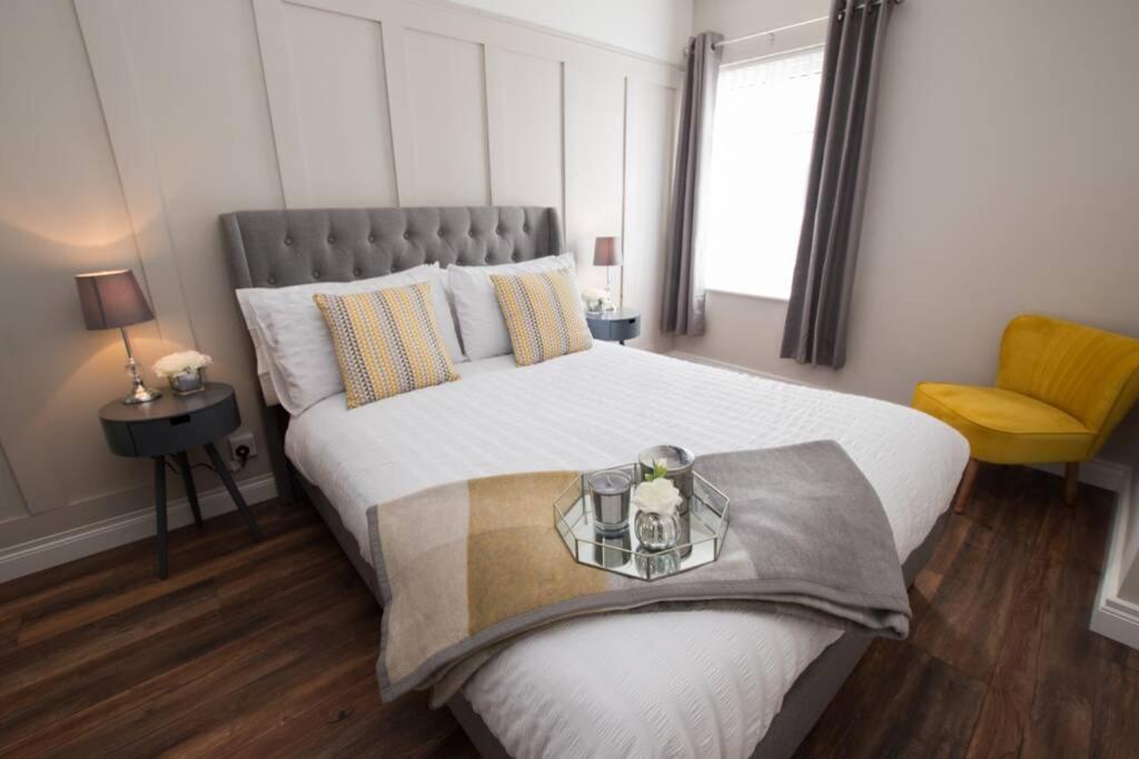 a bedroom with a large white bed and a yellow chair at Atlantic View Apartment in Dungloe