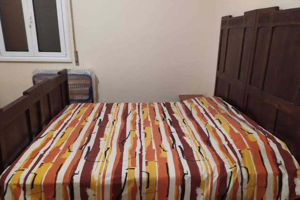 a bed with a striped comforter in a bedroom at Appartamento Limone in Lido di Ostia