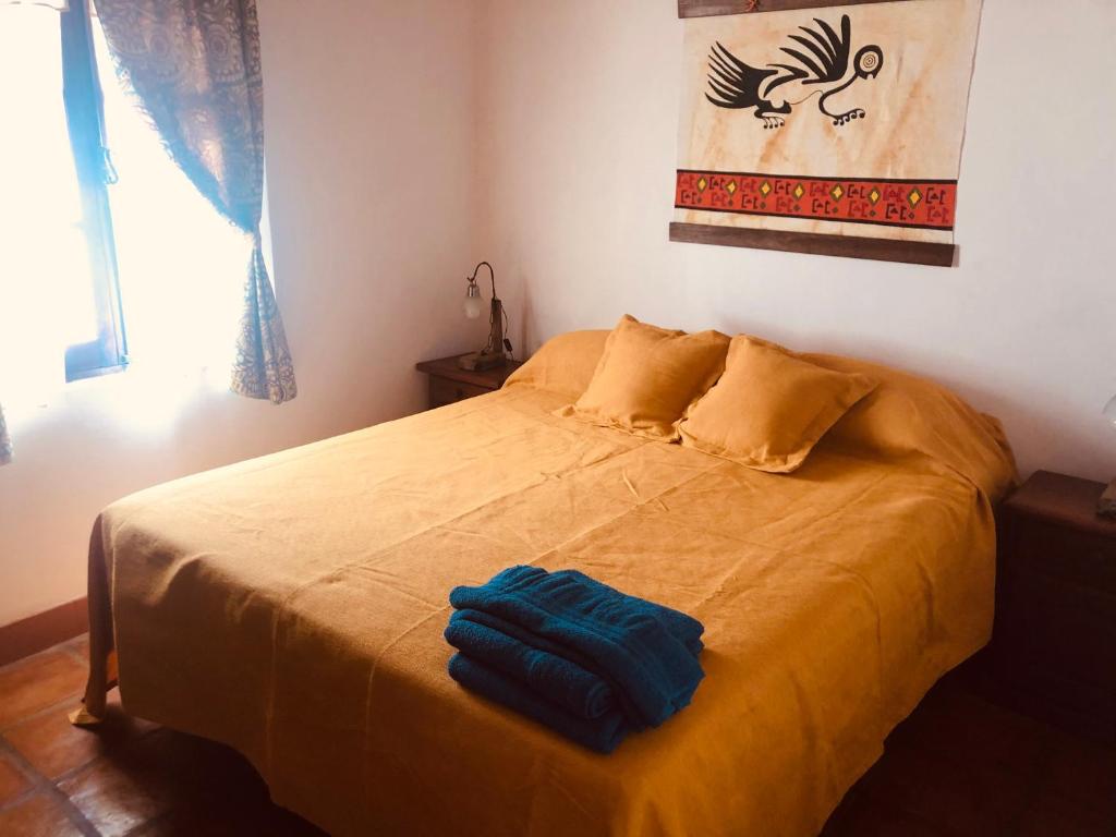 um quarto com uma cama com um cobertor amarelo em Refugios del Callejón em San Carlos