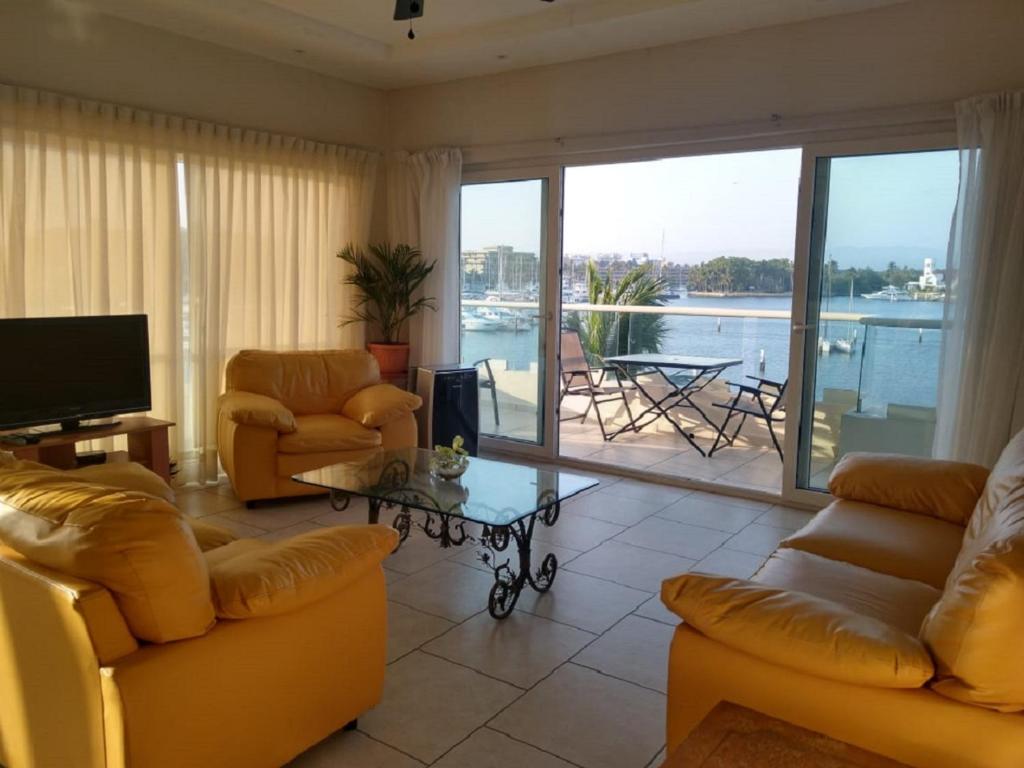 a living room with yellow furniture and a view of the water at Marina Banderas Suites Hotel Boutique in Nuevo Vallarta 