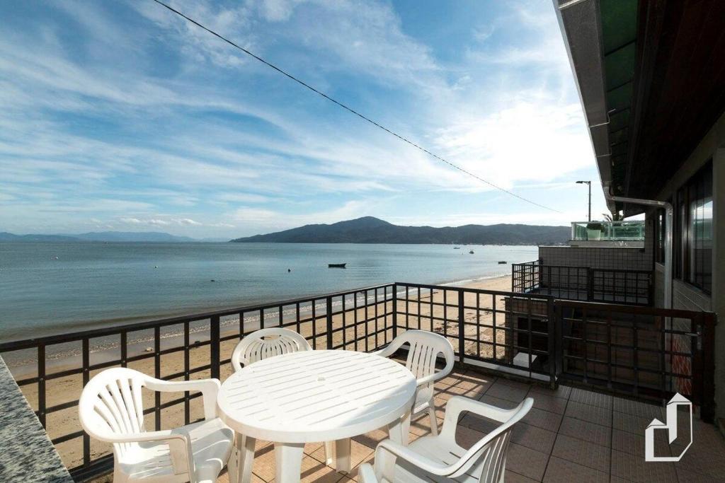 een tafel en stoelen op een balkon met uitzicht op de oceaan bij Casa aconchegante com o pôr-do-sol mais lindo da cidade in Bombinhas