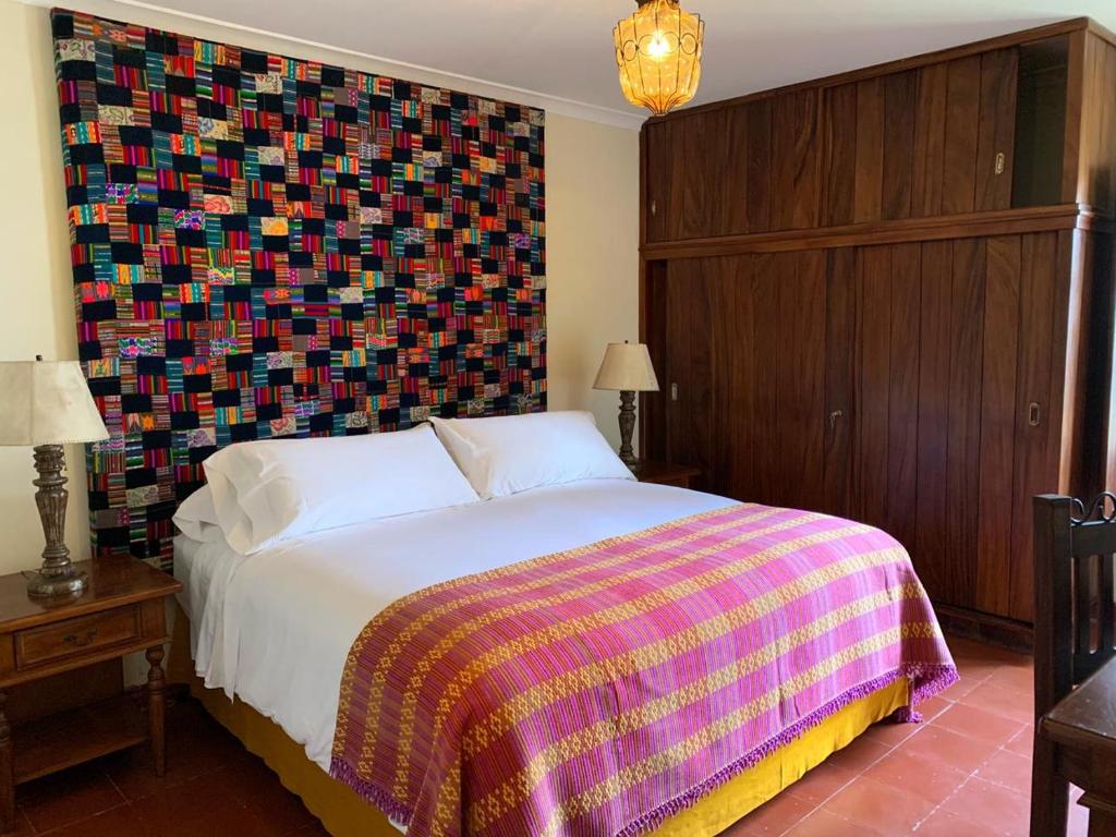 a bedroom with a bed and a colorful wall at Casa Chula / Céntrica con jardín, terraza y parqueo in Antigua Guatemala