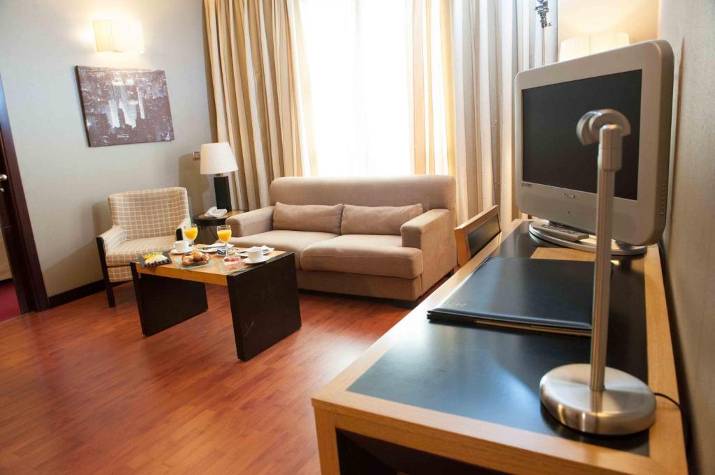 a living room with a television on a table at Sercotel Princesa De Eboli in Pinto