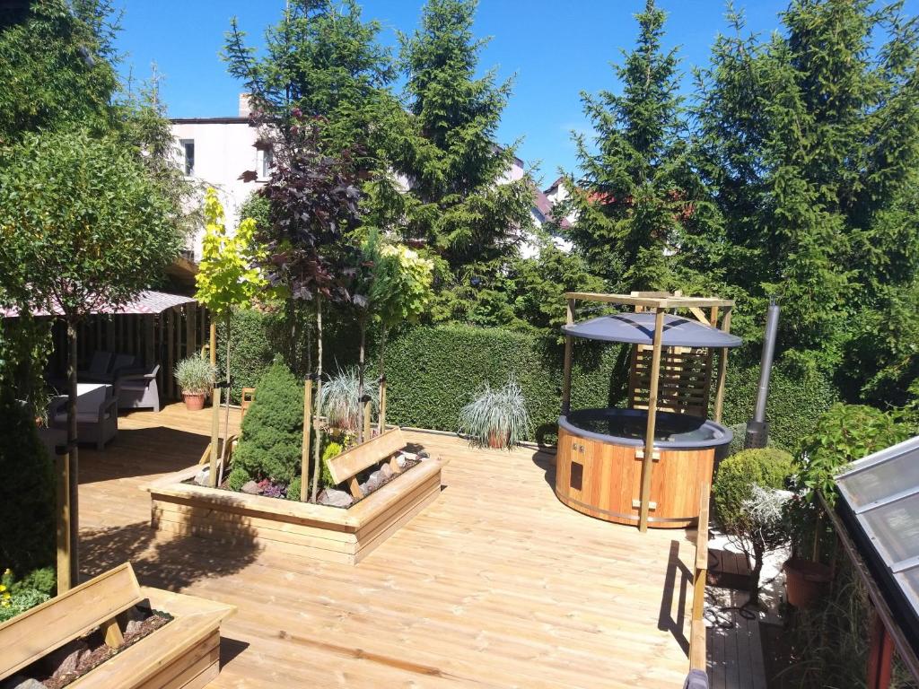 un jardín con una terraza de madera con sombrilla en Domek letniskowy 8 -osobowy en Sianozety