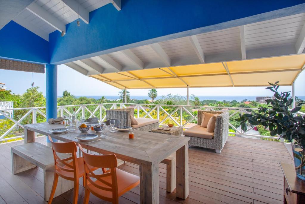 een patio met een houten tafel en stoelen en een grote parasol bij Piscadera Bay Resort 104 in Willemstad