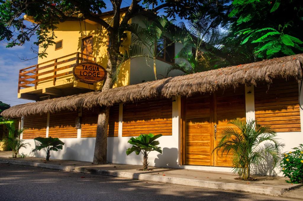 a building with a thatch roof and a sign on it at Tagualodge Hostel Manglaralto in Manglaralto