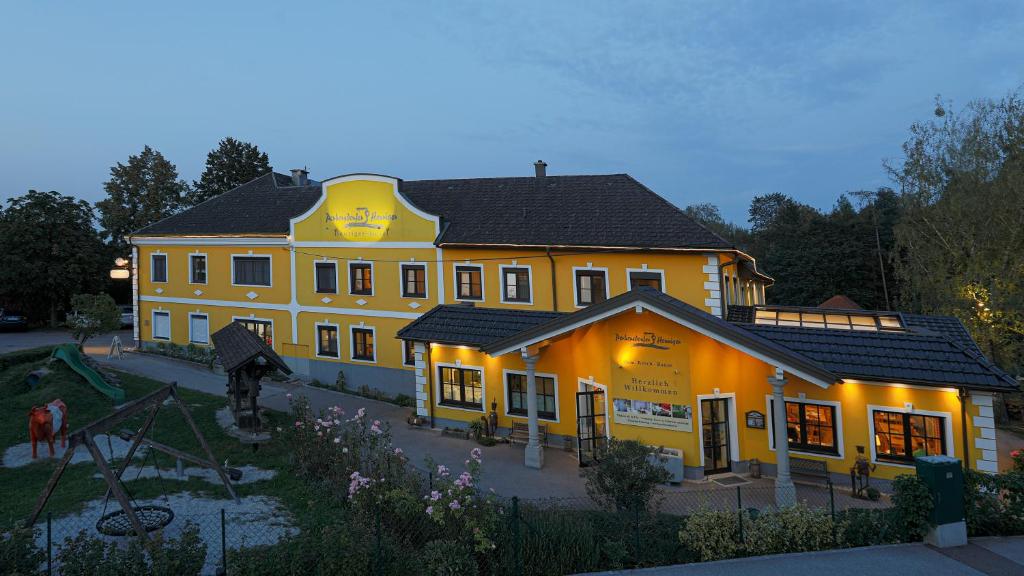 ein großes gelbes Gebäude mit eingeschalteten Lichtern in der Unterkunft Perbersdorfer Heuriger in Neuhofen an der Ybbs